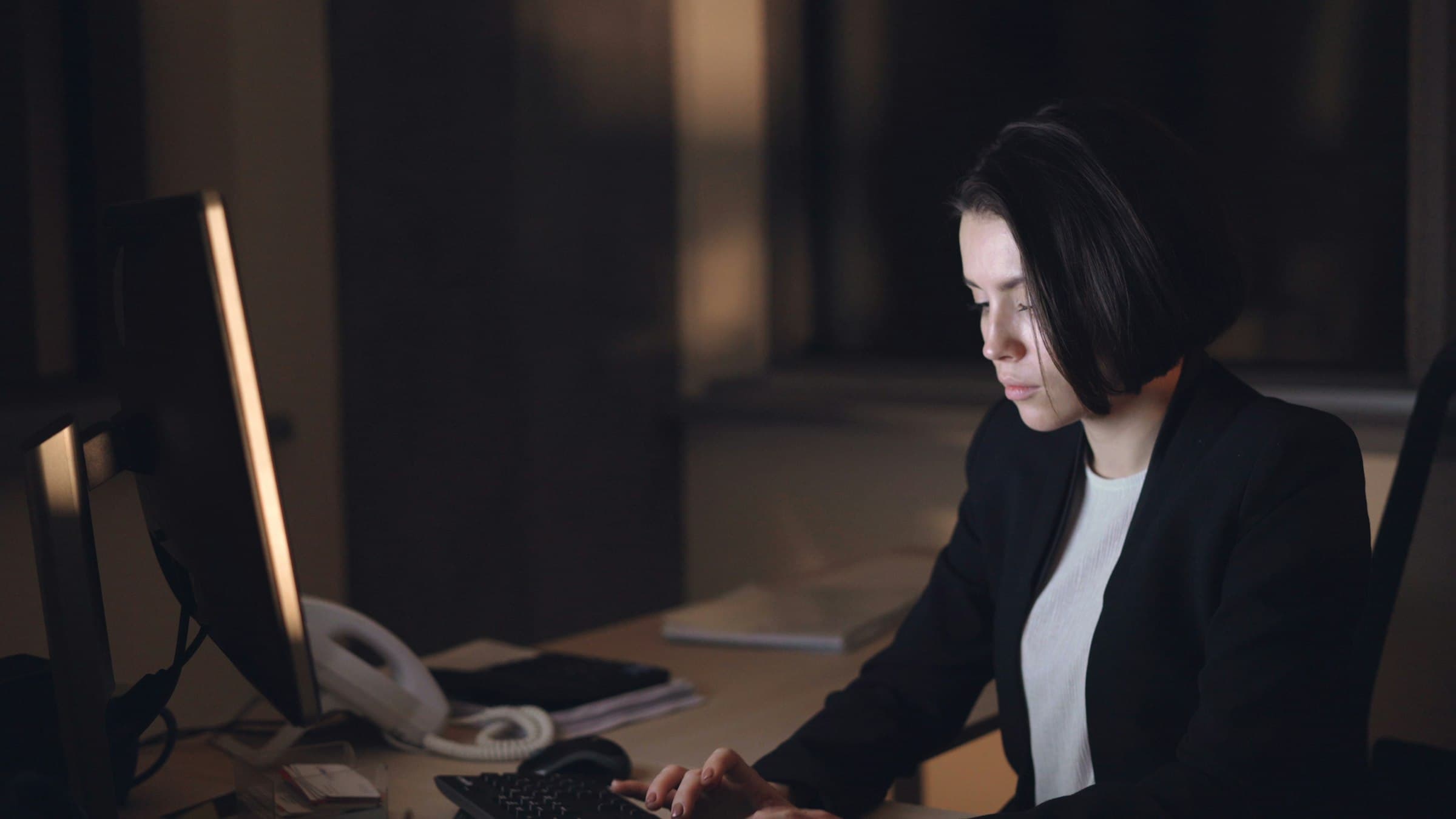 Professional working late at a desktop in a dark office
